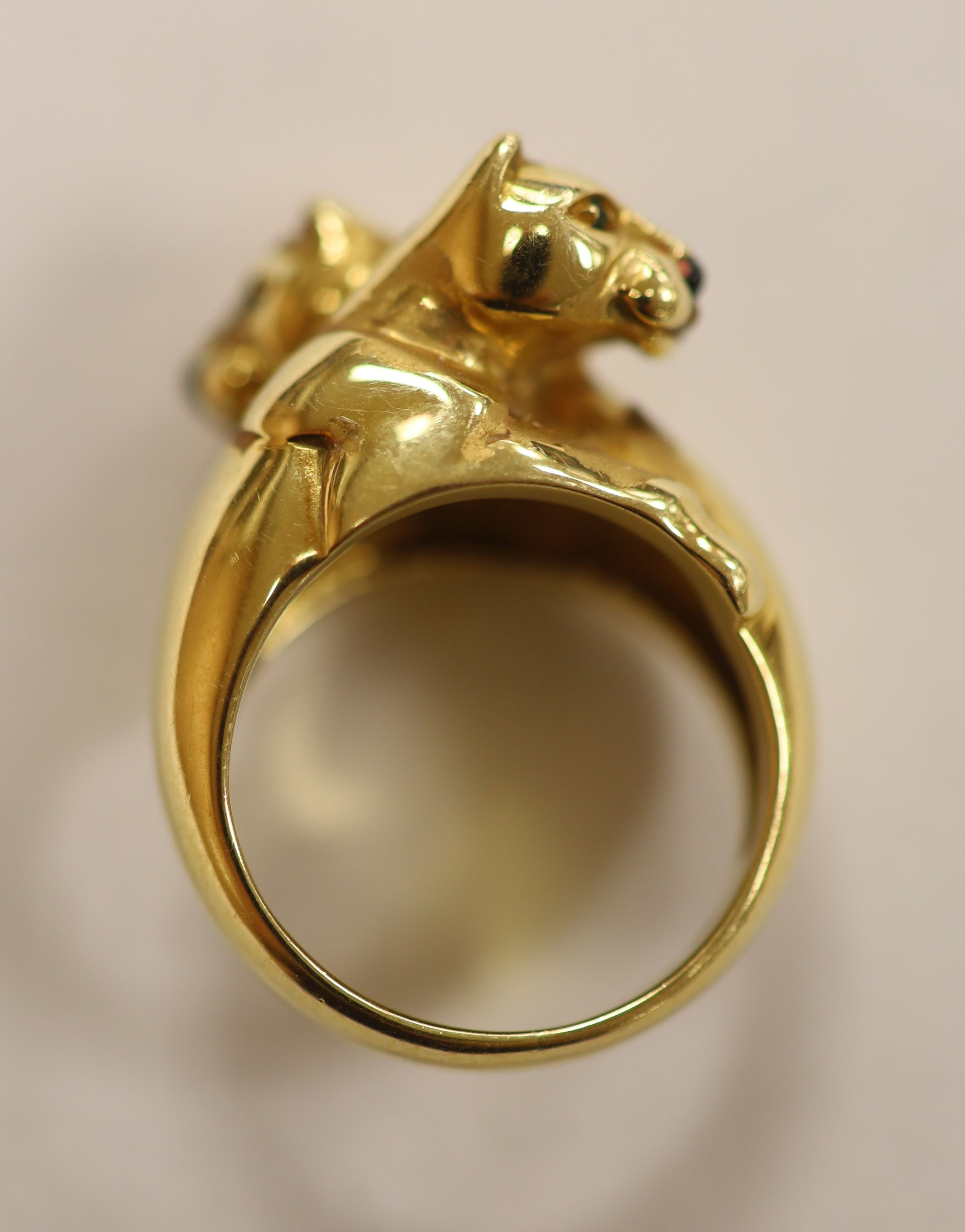 An early 1990's Cartier 18ct gold, black onyx and emerald set twin leopard's head crossover ring